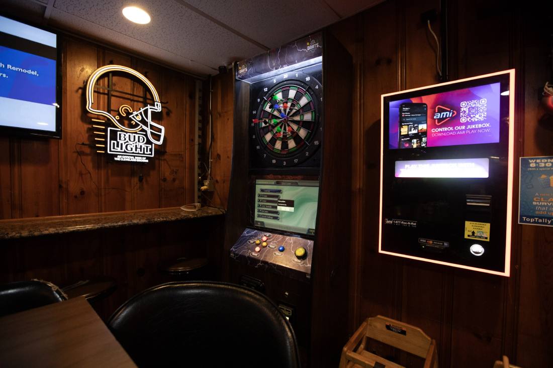The dart corner — electronic dartboard on knotty pine panelling, jukebox alongside and a Cleveland Browns neon on the wall