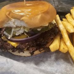 The double smash burger in a paper-lined basket with fries — two seared patties, American cheese, lettuce, pickle and red onion