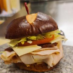The roasted turkey club stacked on a pretzel bun with bacon, Swiss cheese, lettuce and tomato