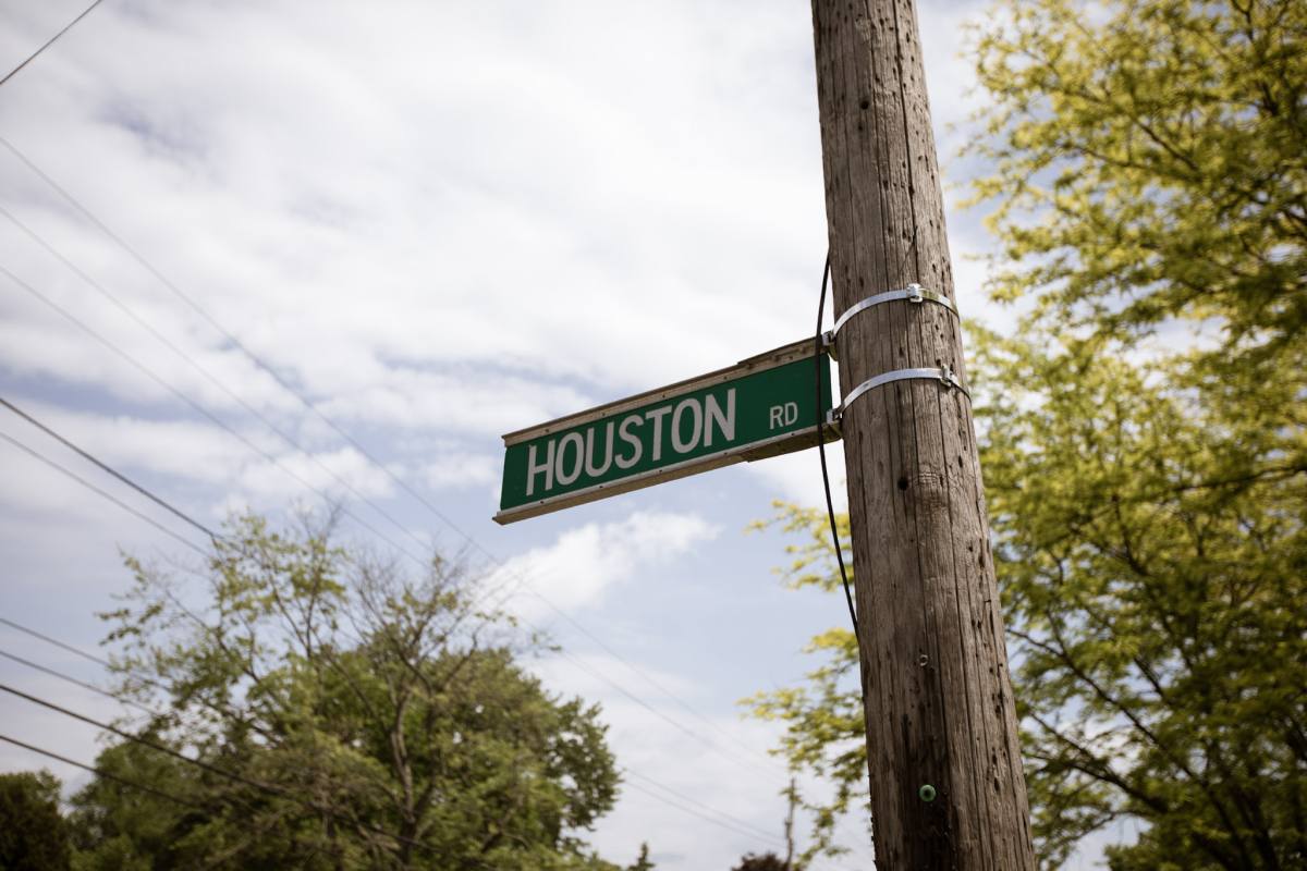 The Houston Rd street sign on its pole against a bright, part-cloudy sky