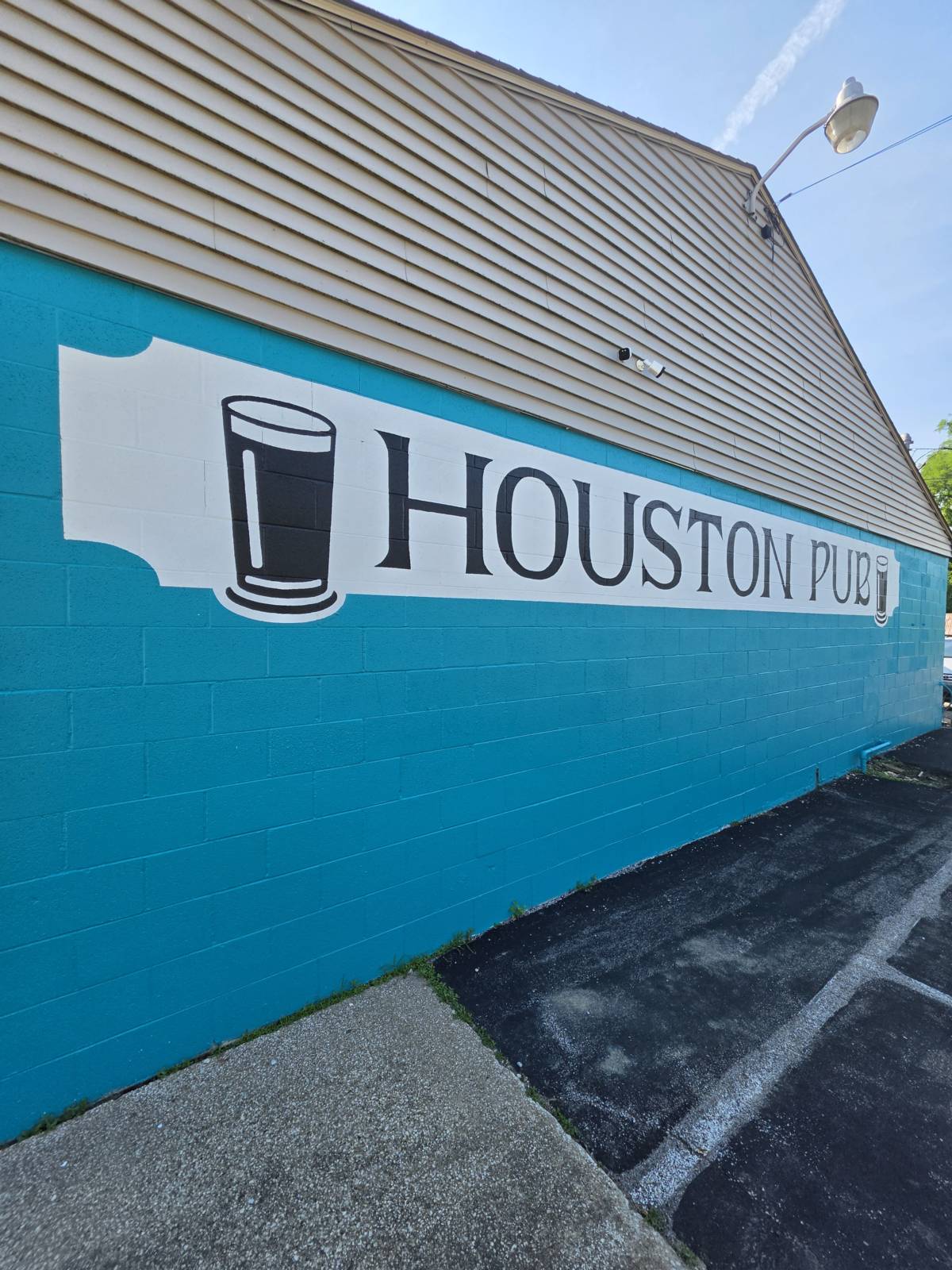 The teal-painted exterior wall with the giant painted HOUSTON PUB wordmark and pint glass